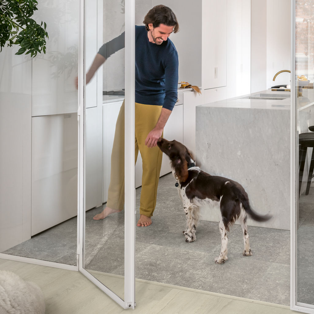 Hombre jugando con su perro en una cocina con suelo laminado Quick-Step Muse Arenisca Azul Oscuro