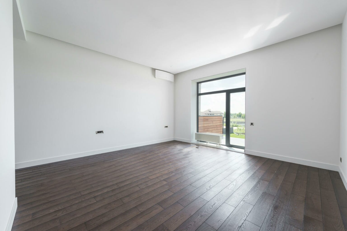 Habitación vacía y luminosa con suelo de parquet oscuro, uno de los estilos disponibles
