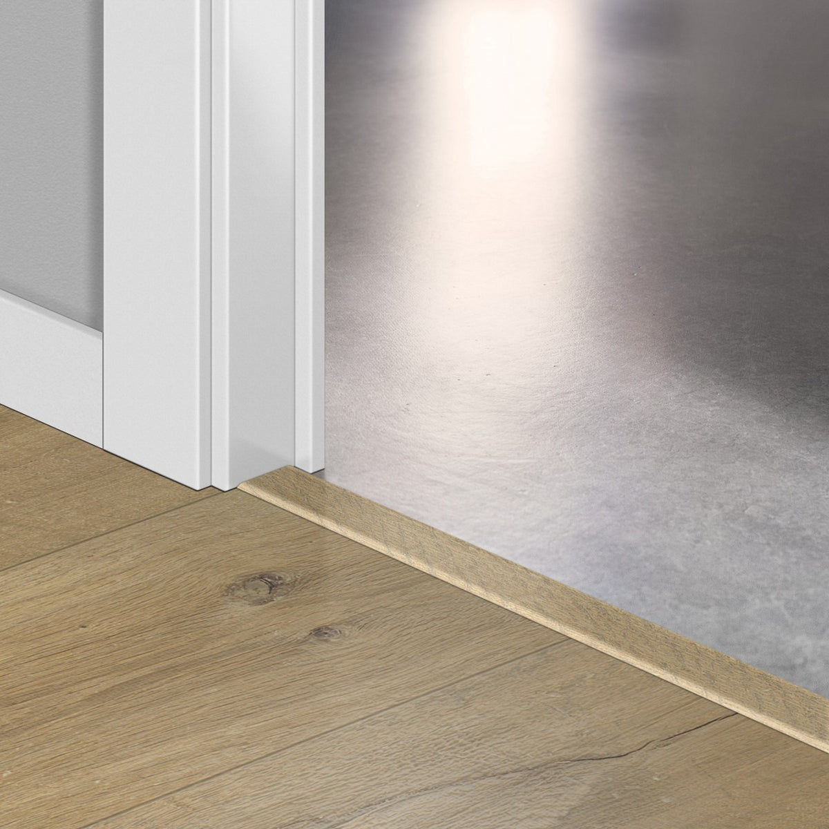 Perfil Quick-Step Incizo a juego del suelo laminado, colocado bajo una puerta (ejemplo en un decor de roble)