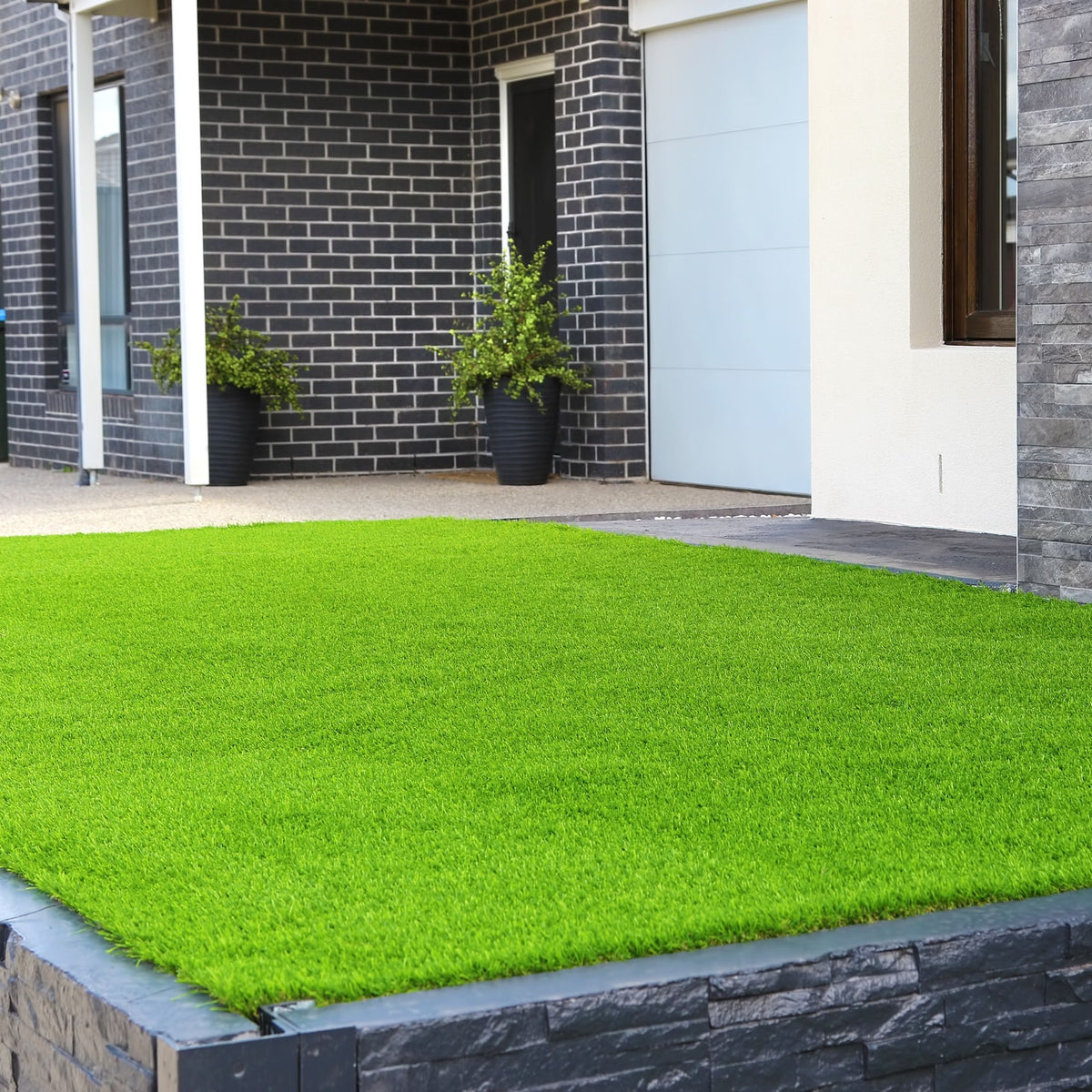 Césped artificial recién instalado en el jardín delantero de una vivienda moderna