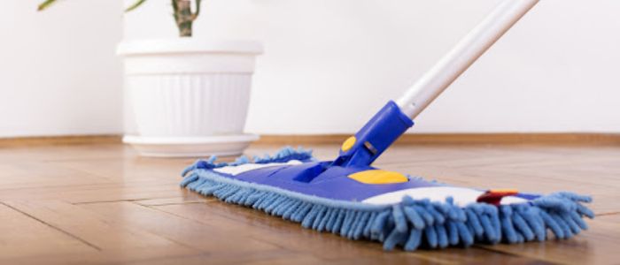 Fregona de microfibra limpiando un suelo laminado de madera, sin necesidad de cera