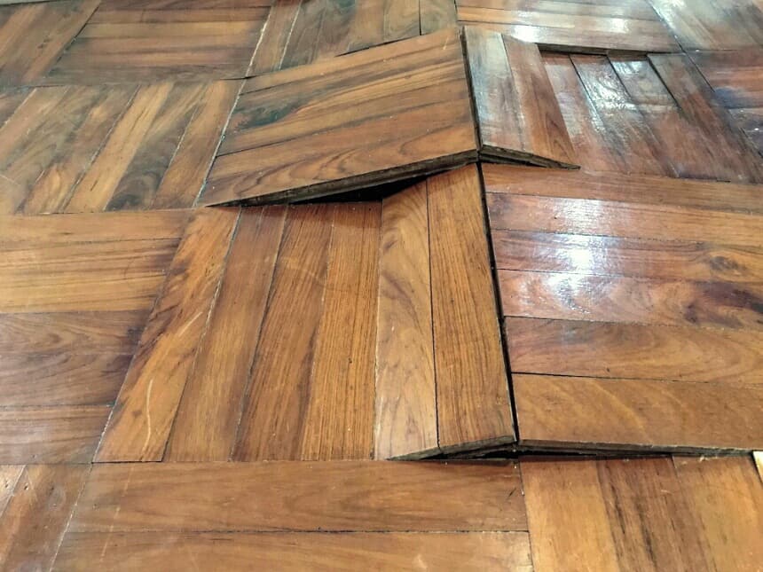 Parquet de madera levantado y abombado por humedad, mostrando el problema explicado