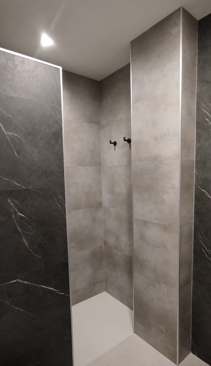 Ángulo de aluminio colocado en las esquinas exteriores de una ducha revestida con placas Tauro Walls efecto cemento
