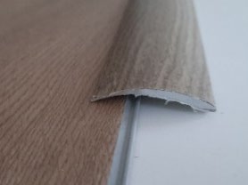 Perfil de adaptación de PVC o aluminio adhesivo, color a juego con el suelo vinílico SPC Mundoparquet 4000 (2700 x 38 mm), colocado en el borde del suelo